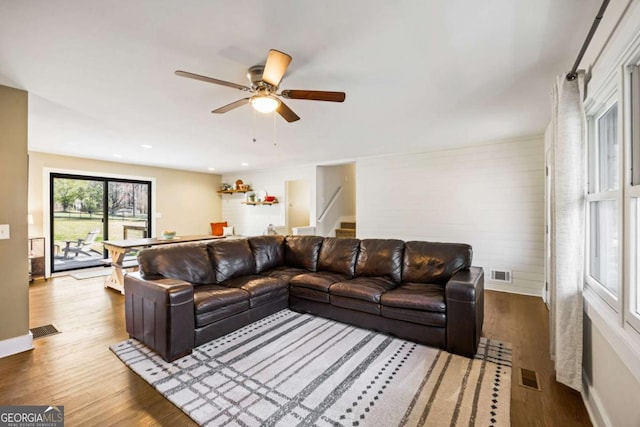 living area featuring stairs, visible vents, and wood finished floors