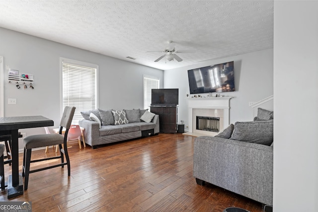 85 Clairidge Ln, Lawrenceville, GA 30046 - living area featuring a fireplace with raised hearth, a textured ceiling, dark wood-style floors, visible vents, and ceiling fan