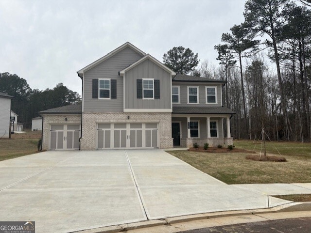 view of front of home featuring driveway, a front yard, board and batten siding, brick siding, and a garage