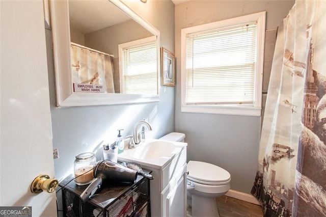 full bath with baseboards, wood finished floors, toilet, and vanity