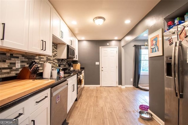 kitchen with white cabinetry, tasteful backsplash, light wood-type flooring, and appliances with stainless steel finishes