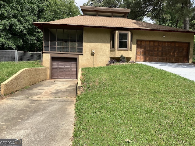 prairie-style home featuring driveway, a front yard, fence, a shingled roof, and stucco siding