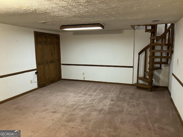 finished basement with carpet, stairs, a textured ceiling, and visible vents