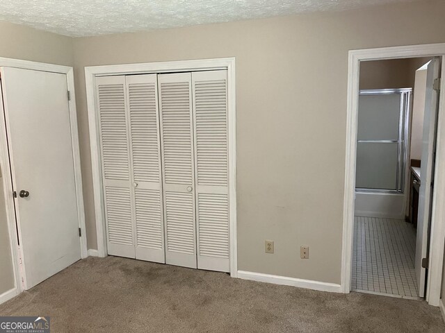 1288 Lakewood Dr NE, Conyers, GA 30013 - unfurnished bedroom featuring a closet, baseboards, connected bathroom, a textured ceiling, and carpet flooring