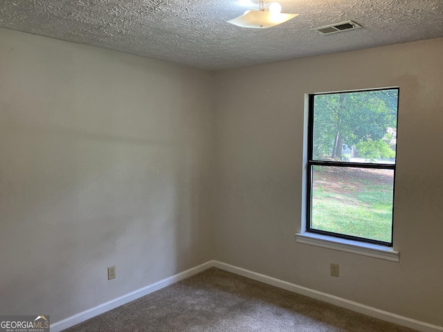 unfurnished room featuring carpet floors, baseboards, a textured ceiling, and visible vents