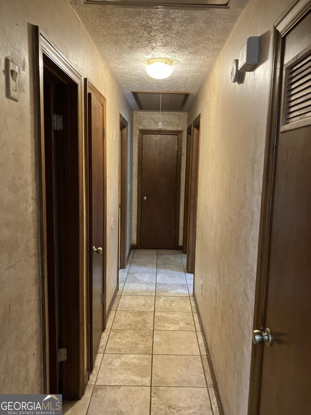 1288 Lakewood Dr NE, Conyers, GA 30013 - hallway with attic access, a textured ceiling, a textured wall, and light tile patterned flooring