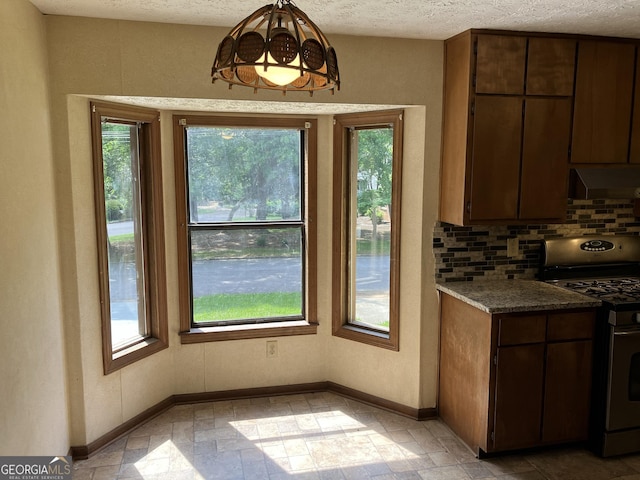 kitchen featuring stainless steel range with gas stovetop, decorative backsplash, a healthy amount of sunlight, and extractor fan