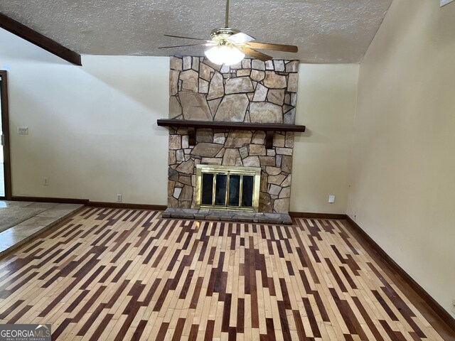 1288 Lakewood Dr NE, Conyers, GA 30013 - unfurnished living room with ceiling fan, a stone fireplace, a textured ceiling, wood finished floors, and baseboards