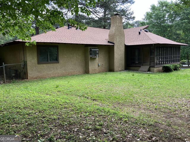 1288 Lakewood Dr NE, Conyers, GA 30013 - rear view of house featuring a chimney, a sunroom, fence, a shingled roof, and stucco siding