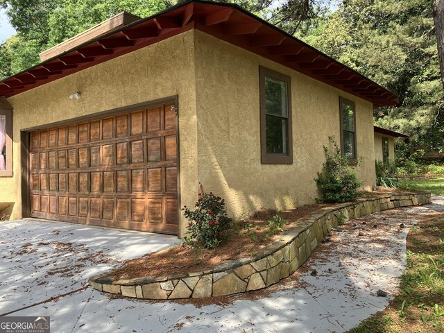 view of property exterior with a garage, stucco siding, and driveway