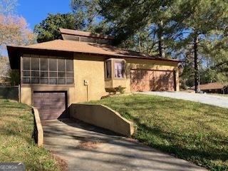 view of front of home featuring an attached garage, driveway, stucco siding, and a front yard