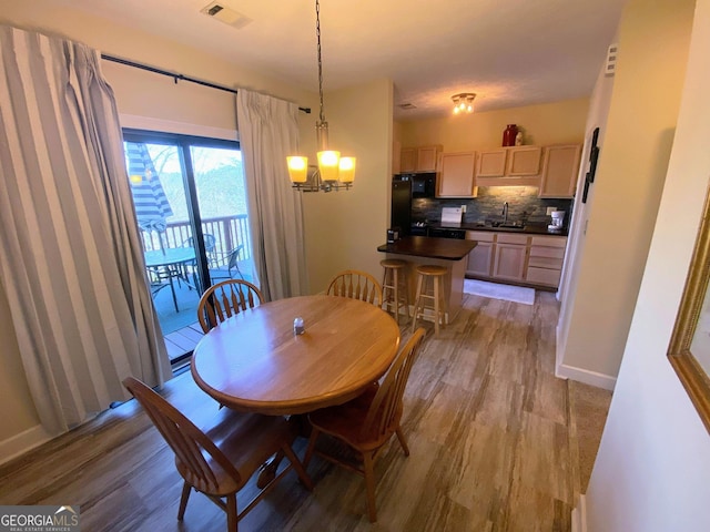 dining area featuring baseboards, visible vents, an inviting chandelier, and wood finished floors