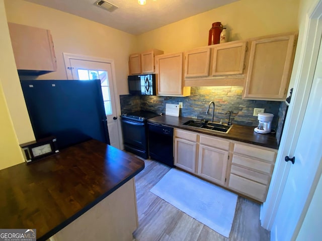 kitchen with tasteful backsplash, light brown cabinetry, a sink, visible vents, and black appliances