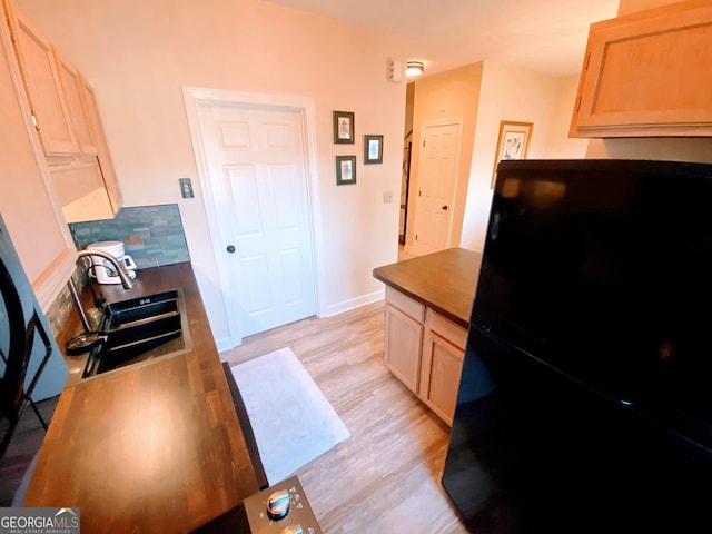 kitchen featuring baseboards, butcher block counters, a sink, light wood-style floors, and freestanding refrigerator