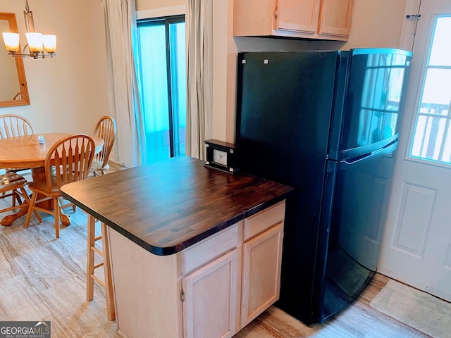 kitchen featuring light wood finished floors, butcher block counters, a chandelier, and freestanding refrigerator