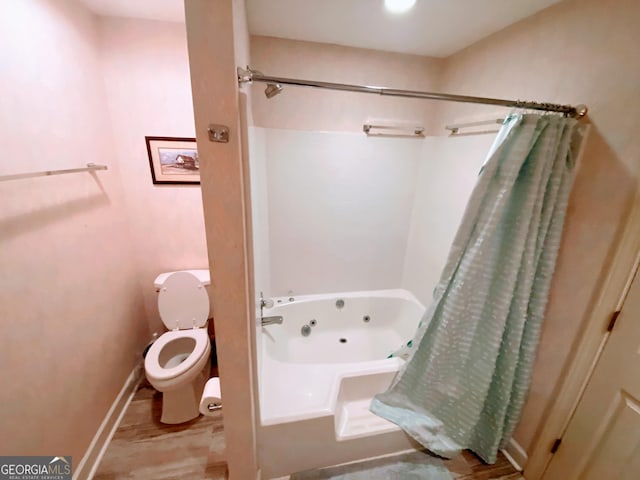 bathroom featuring baseboards, a combined bath / shower with jetted tub, and toilet