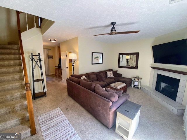 living room featuring carpet, ceiling fan, stairway, and a textured ceiling