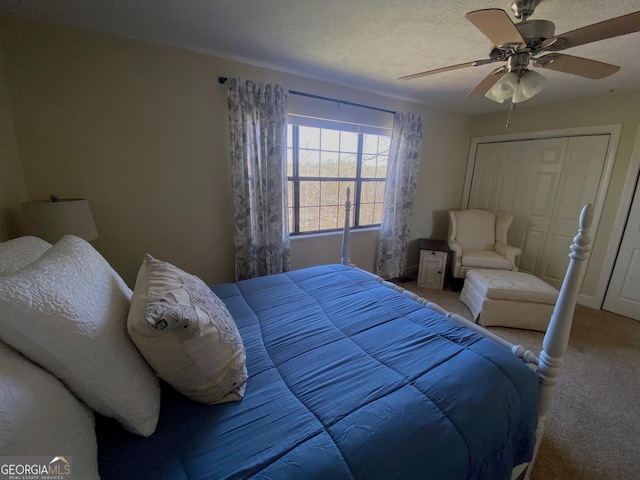 carpeted bedroom with a closet, ceiling fan, and a textured ceiling