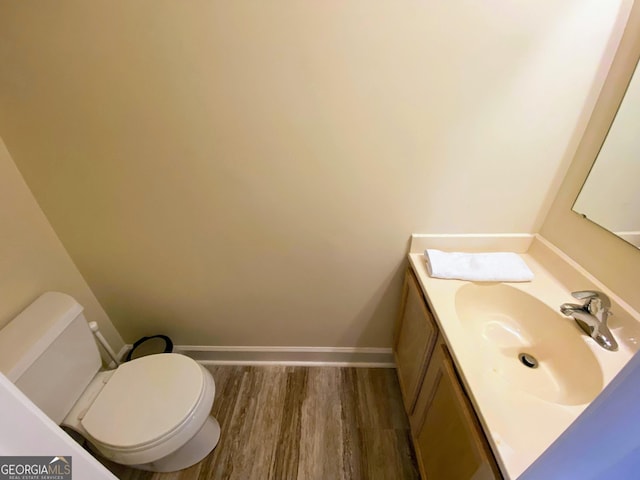 bathroom featuring toilet, vanity, baseboards, and wood finished floors