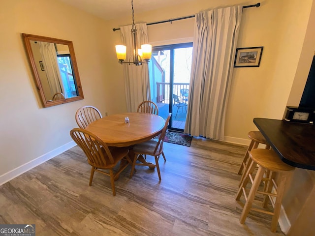 dining room with baseboards, wood finished floors, and an inviting chandelier