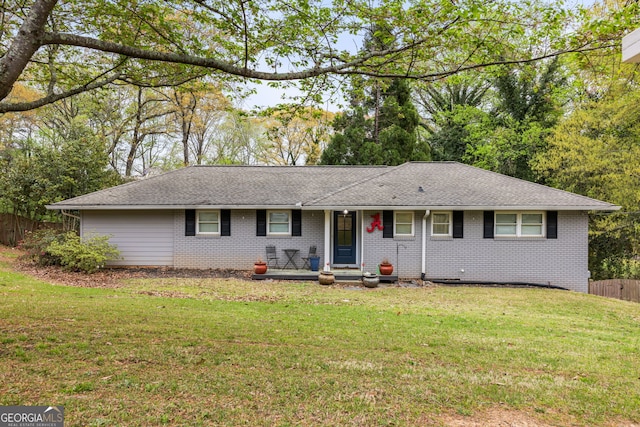 single story home featuring a shingled roof, a front yard, fence, and brick siding