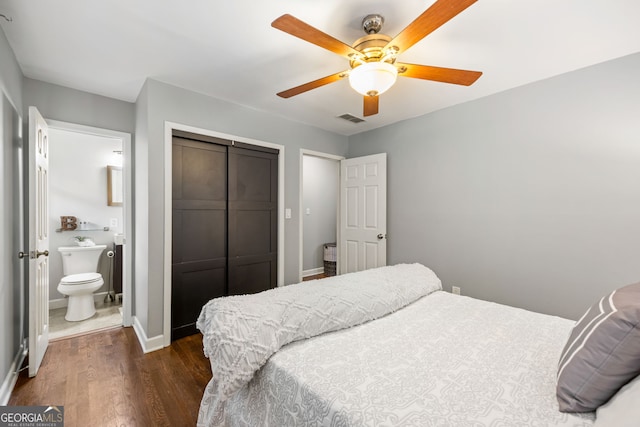 bedroom with a closet, dark wood-style flooring, ensuite bathroom, visible vents, and baseboards