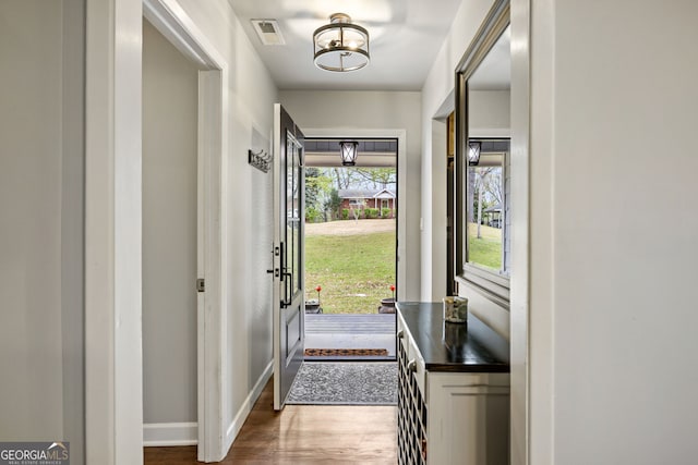 entryway featuring dark wood finished floors, baseboards, and visible vents