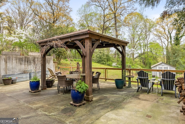 view of patio / terrace featuring a gazebo, outdoor dining area, an outdoor structure, and a storage shed