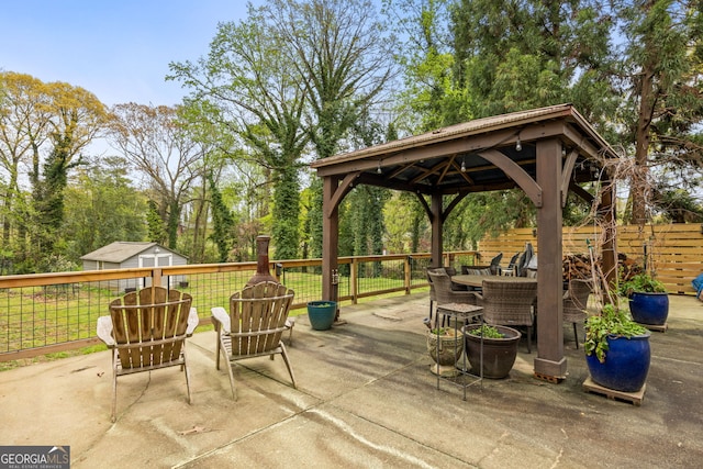 view of patio featuring a gazebo, outdoor dining area, and fence