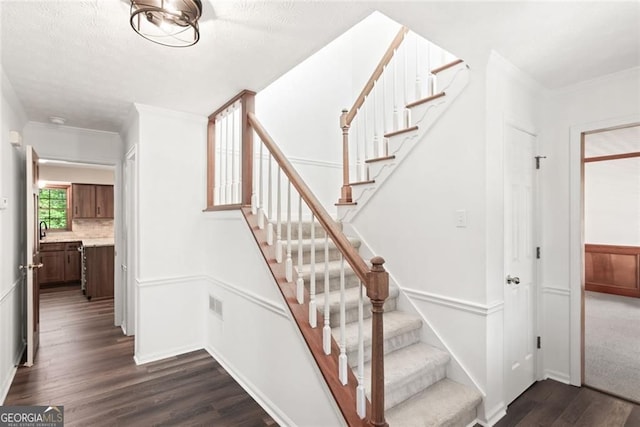 2731 Old Coach Rd, Duluth, GA 30096 - stairway featuring wood finished floors, crown molding, wainscoting, and a textured ceiling