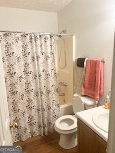 full bath featuring wood finished floors, a textured ceiling, vanity, shower / bathtub combination with curtain, and toilet