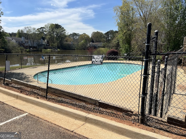community pool featuring a water view and fence