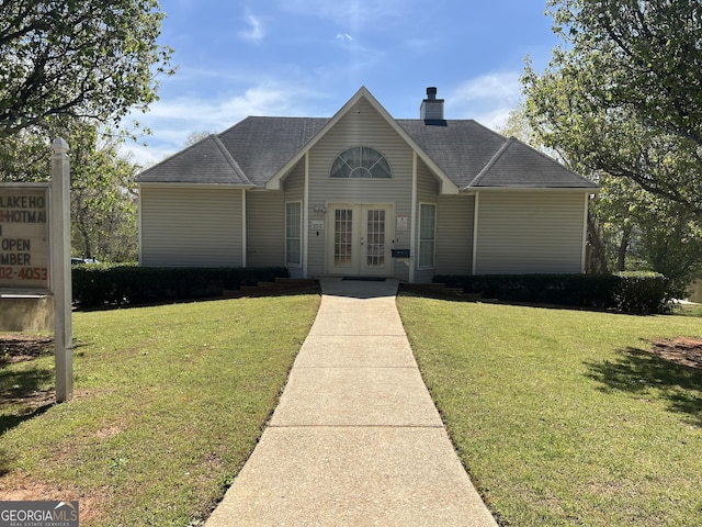 ranch-style house with french doors, roof with shingles, a chimney, and a front yard