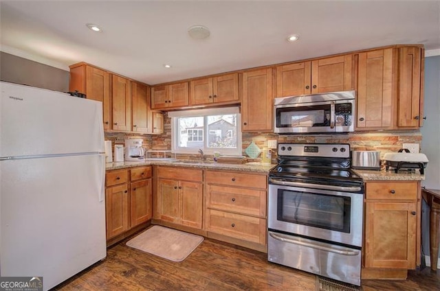 kitchen featuring appliances with stainless steel finishes, tasteful backsplash, dark wood-style flooring, light stone counters, and recessed lighting