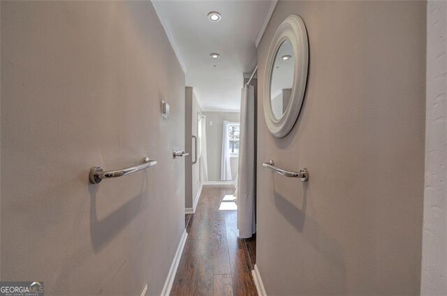 hallway with dark wood-style flooring, crown molding, and baseboards