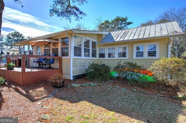 back of property with a standing seam roof, metal roof, and a sunroom
