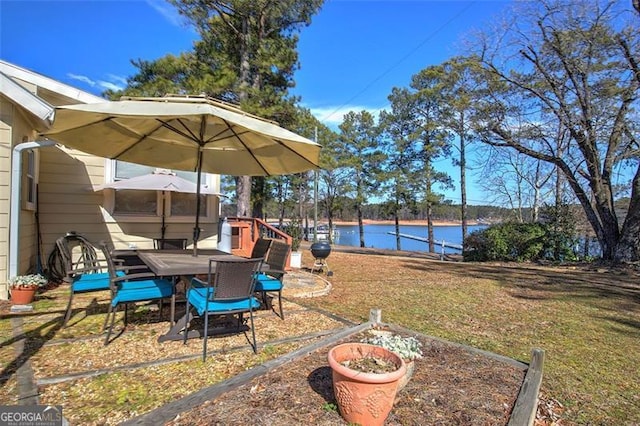 view of grassy yard with a water view, a patio area, and outdoor dining space
