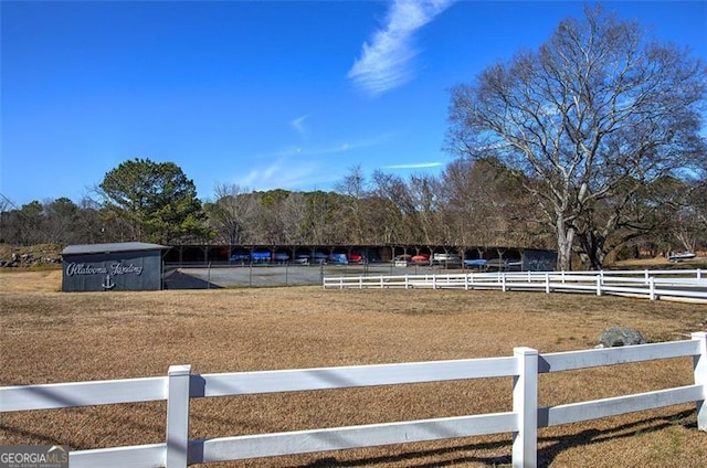view of yard with an enclosed riding area, fence, and view of scattered trees