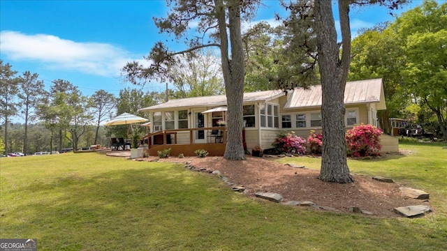 back of house with a sunroom, a yard, and metal roof