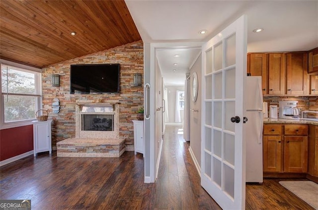 living area with vaulted ceiling, a fireplace, dark wood-style floors, and baseboards