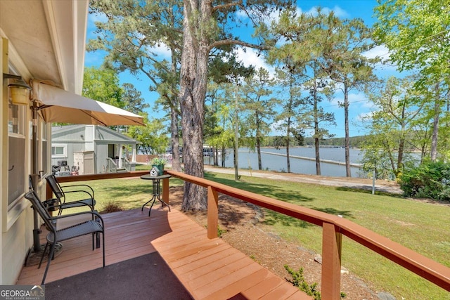wooden terrace with a water view and a yard