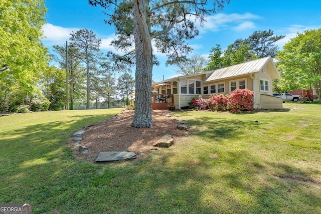 view of green lawn with a sunroom