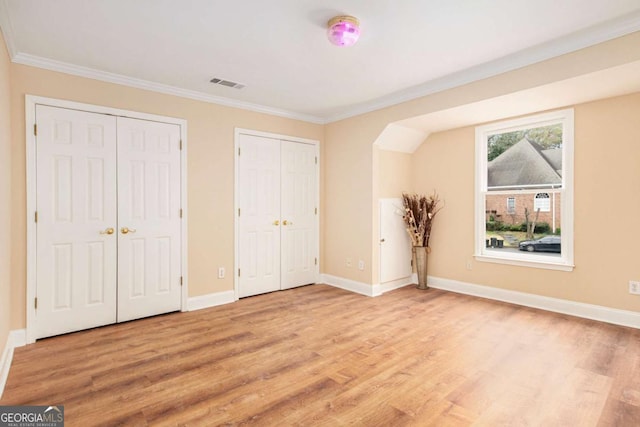 4236 Providence Ln, Tucker, GA 30084 - unfurnished bedroom with multiple closets, visible vents, light wood finished floors, baseboards, and ornamental molding
