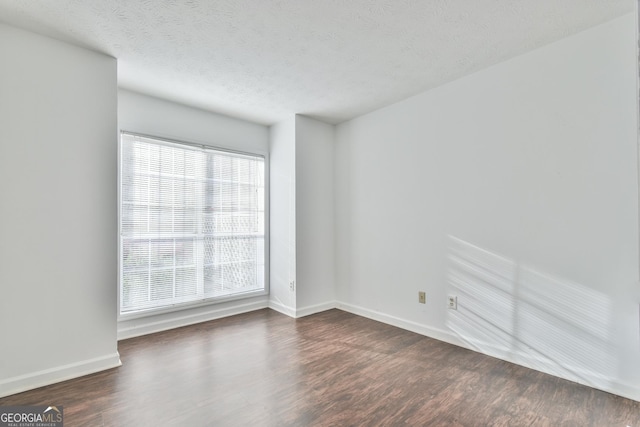 unfurnished room featuring dark wood finished floors, baseboards, and a textured ceiling