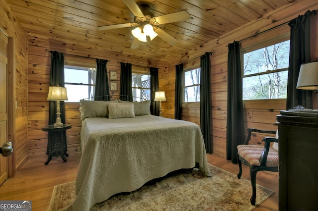 bedroom with wood walls, multiple windows, and wooden ceiling