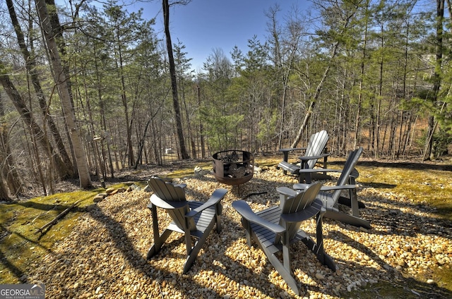 view of yard featuring a fire pit and a forest view