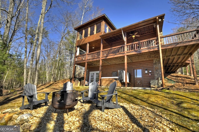back of house featuring faux log siding, a fire pit, a wooden deck, and french doors
