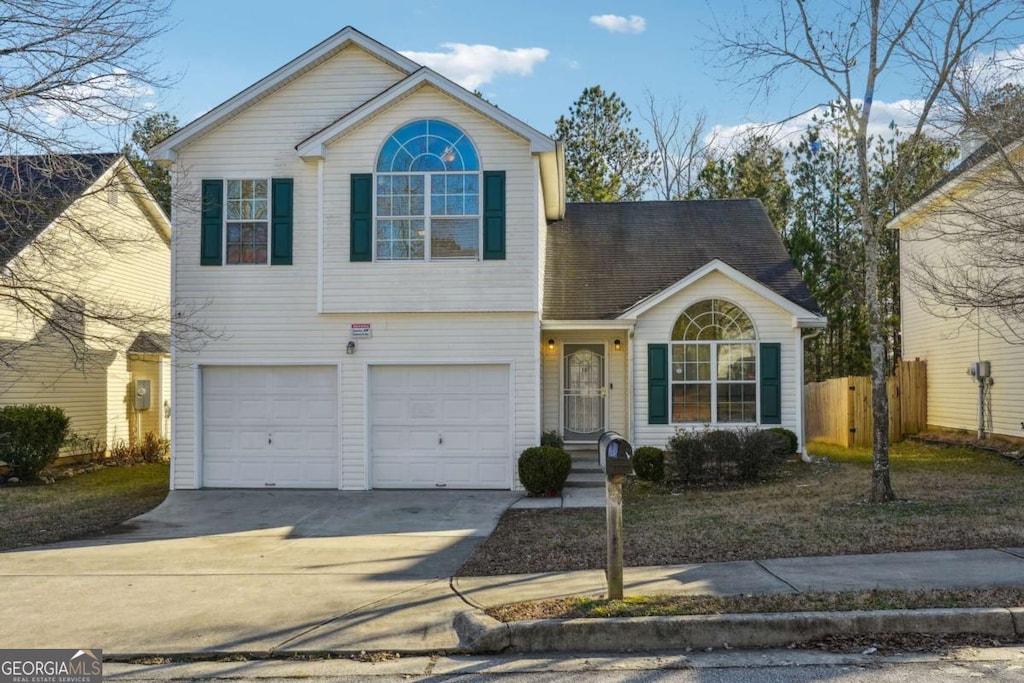 traditional-style house featuring fence, an attached garage, and concrete driveway
