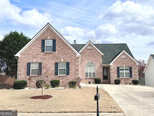 traditional-style home featuring brick siding and fence