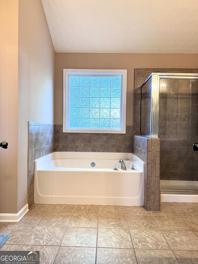 bathroom featuring a bath, tile patterned flooring, a stall shower, lofted ceiling, and a textured ceiling